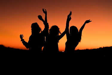 Three women jumping while looking at the sunset
