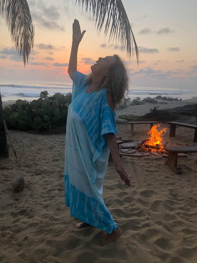 a woman dancing near a campfire at the beach