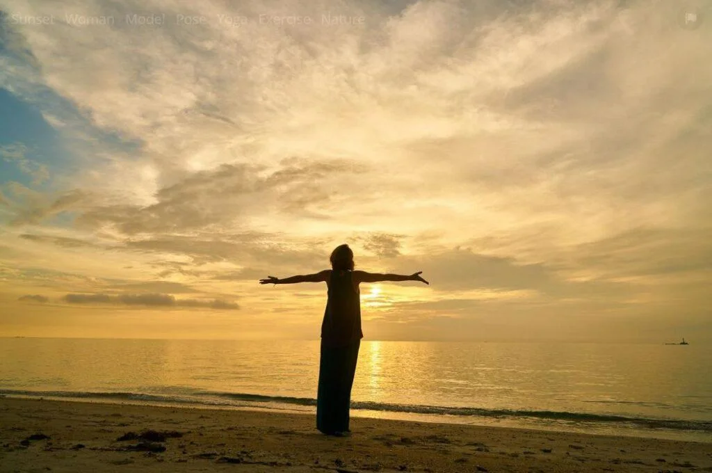 A person standing on the beach with arms outstretched.